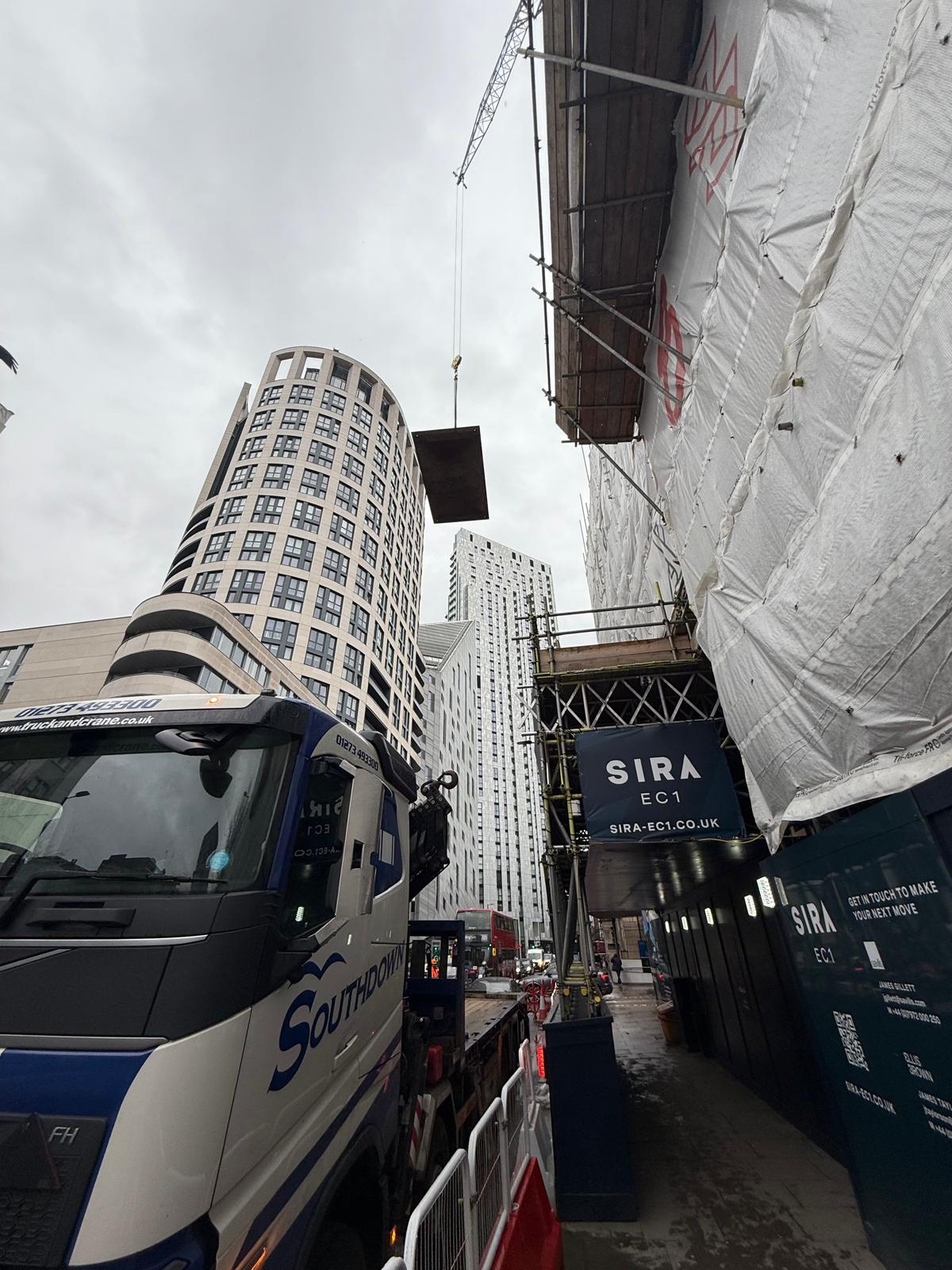 The Southdown team lift a road plate high above a busy London street